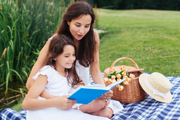 Madre e hija leyendo libro en picnic