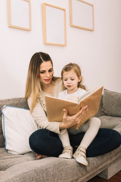 Madre e hija leyendo el libro en la sala de estar