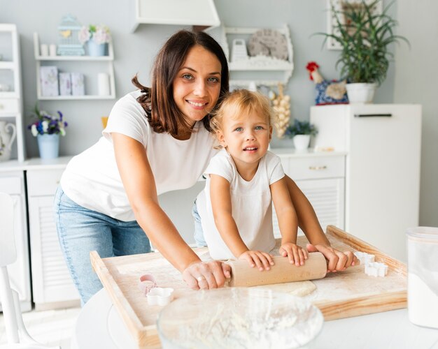 Madre e hija linda con rodillo de cocina