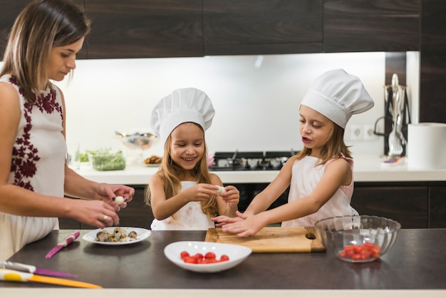 Madre e hija linda sonriente pelando huevos de codorniz cocidos en encimera de cocina