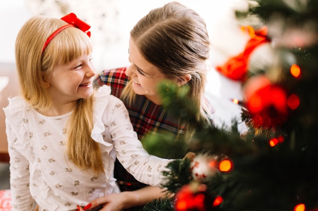 Madre e hija lindas decorando árbol de navidad