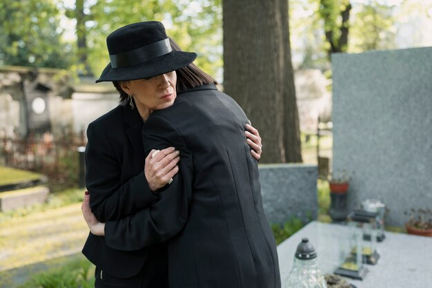 Madre e hija de luto en una tumba en el cementerio