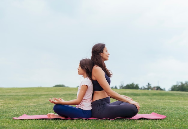 Madre e hija meditando al aire libre