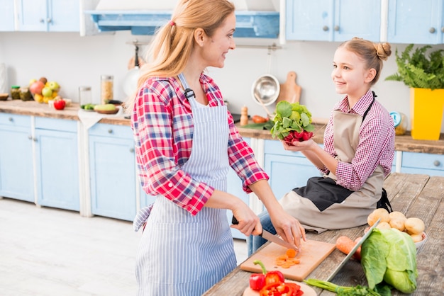 Madre e hija mirándose mientras preparan la comida en la cocina