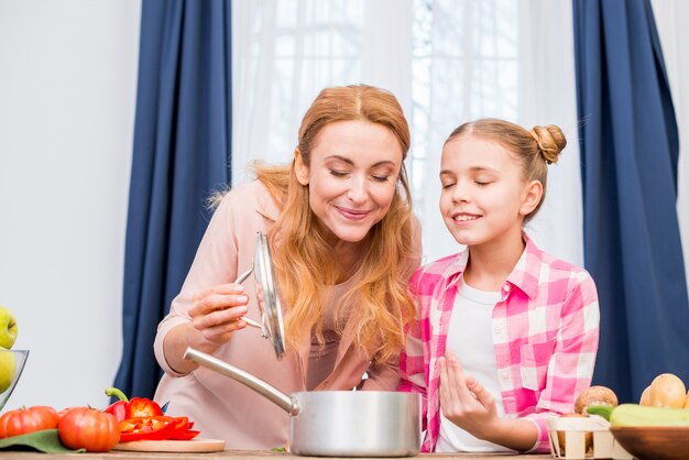 Madre e hija oliendo la comida preparada en la cocina.