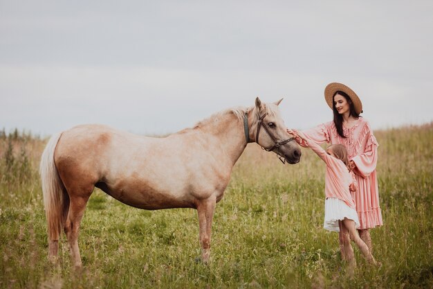 Madre e hija se paran en el campo antes de un caballo