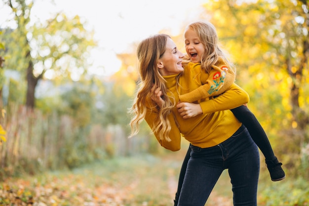 Madre e hija en el parque lleno de hojas