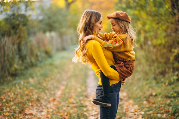 Madre e hija en el parque lleno de hojas