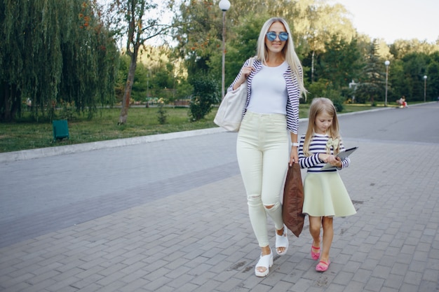 Madre e hija paseando mientras la niña mira una tablet