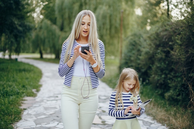 Madre e hija paseando con tablet y teléfono inteligente