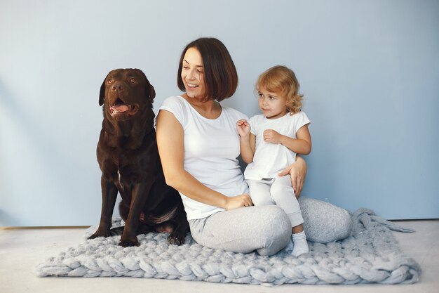 Madre e hija pequeña jugando con perro en casa