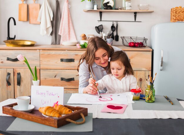 Madre e hija pintando el corazón en la mesa