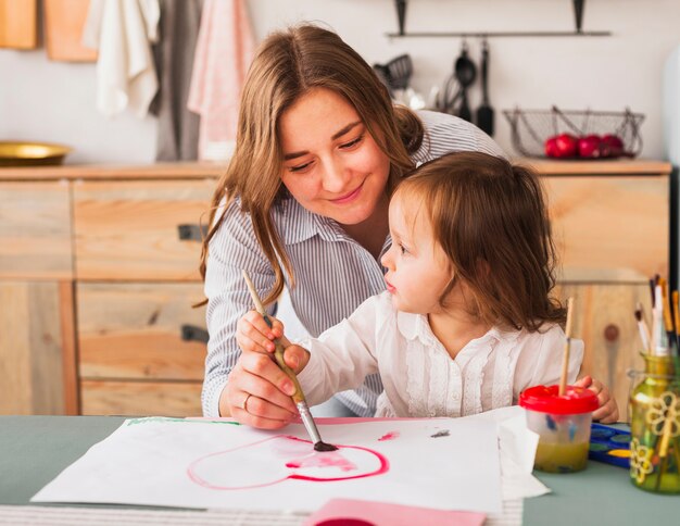 Madre e hija pintando corazón en papel