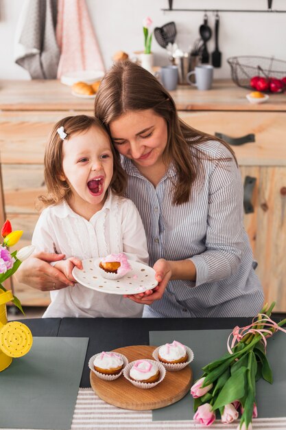 Foto gratuita madre e hija con plato con cupcake