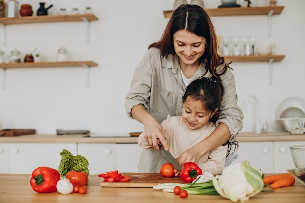 Madre e hija preparando ensalada cocinando en la cocina