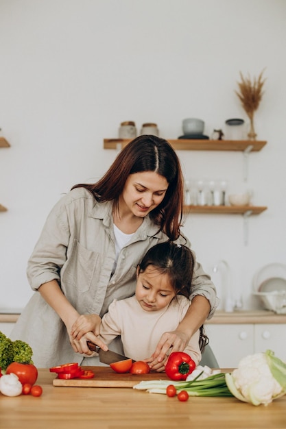 Madre e hija preparando ensalada cocinando en la cocina