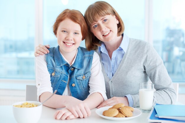 Madre e hija que desayunando en la cocina