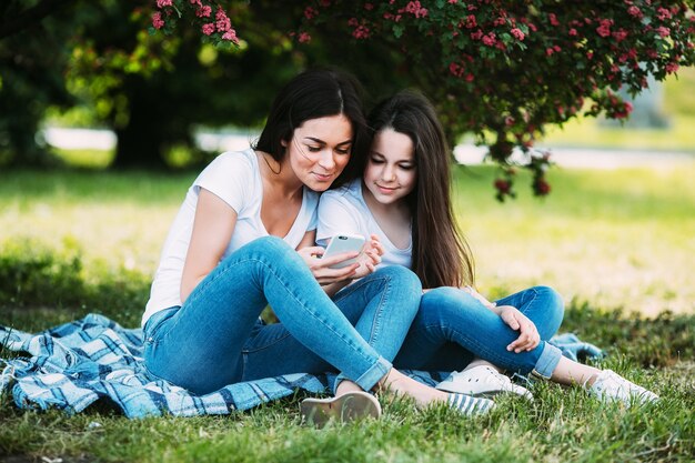 Madre e hija que se sientan en parque que se relaja