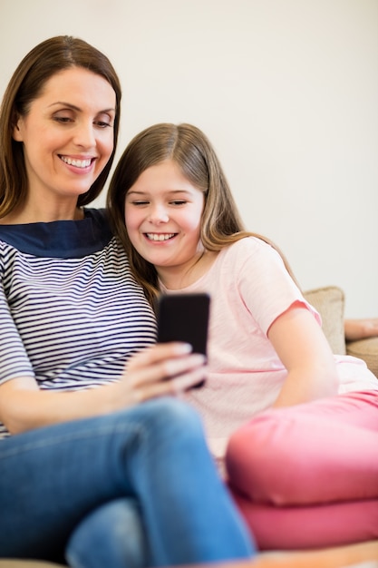 Foto gratuita madre e hija que usa el móvil en la sala de estar