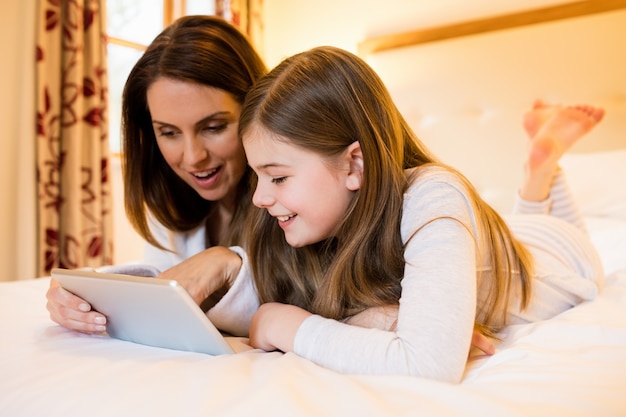 Madre e hija que usa la tableta digital en el dormitorio