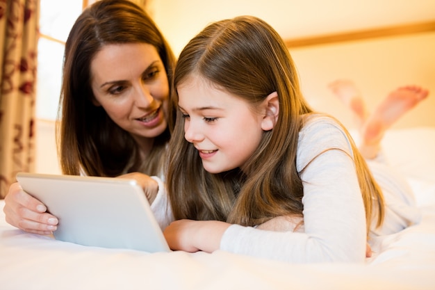 Madre e hija que usa la tableta digital en el dormitorio