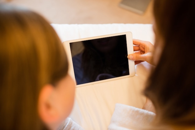 Madre e hija que usa la tableta digital en el dormitorio