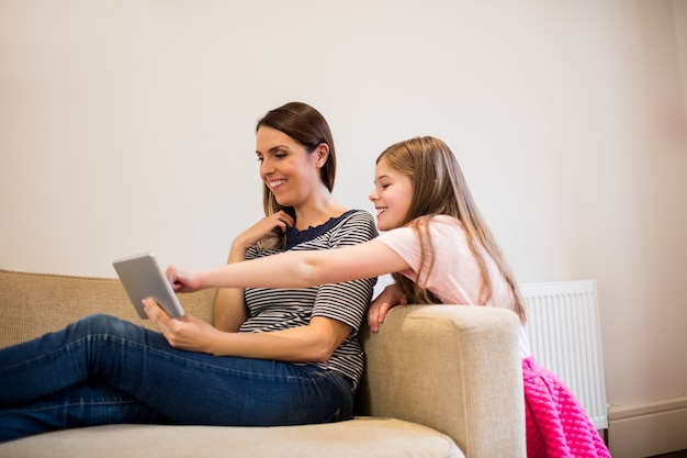 Foto gratuita madre e hija que usa la tableta digital en la sala de estar