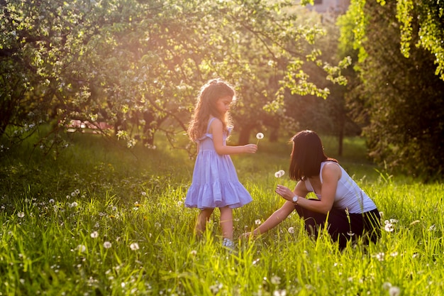 Madre e hija recogiendo flores de diente de león en el parque