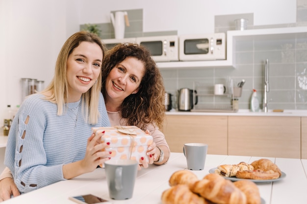 Madre e hija con regalo mirando a cámara