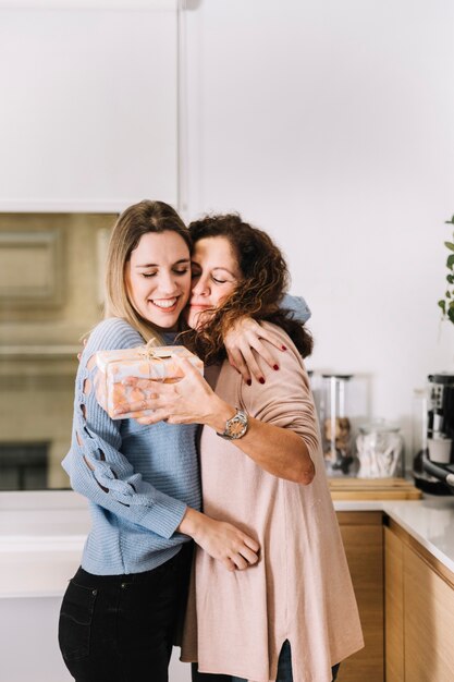 Madre e hija con regalos abrazar en la cocina