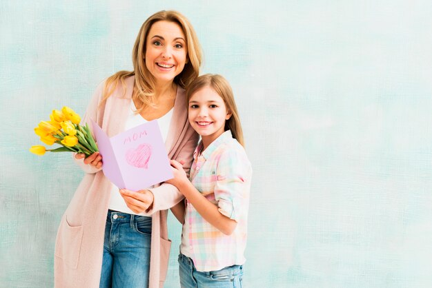 Madre e hija con regalos sonriendo y mirando a cámara