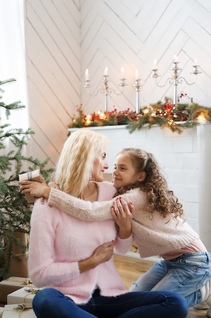 Madre e hija en la sala de estar decorada de Navidad.