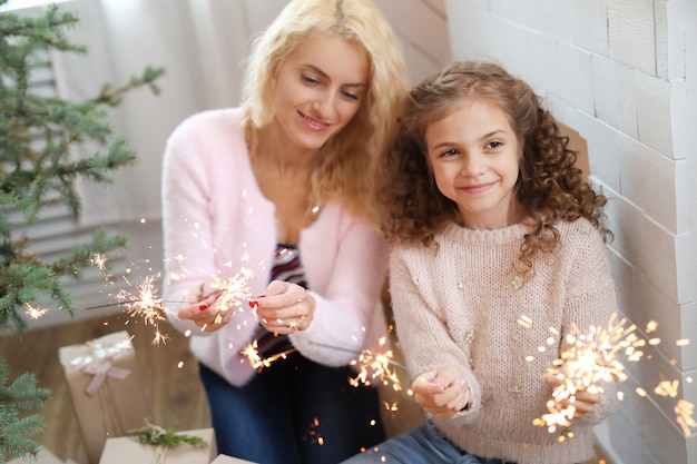 Madre e hija en la sala de estar decorada de Navidad.