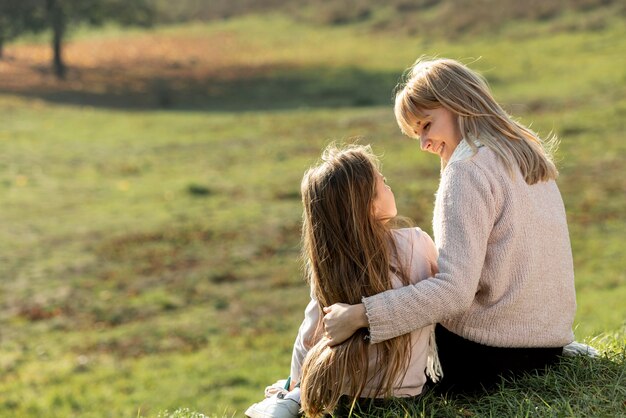 Madre e hija sentada en la naturaleza