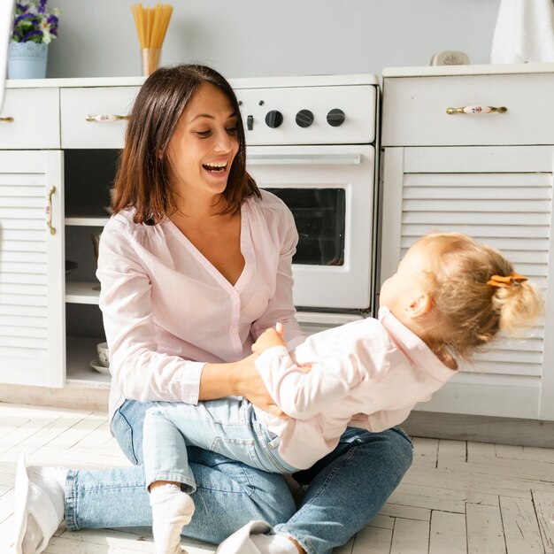 Madre e hija sentada en el piso de la cocina