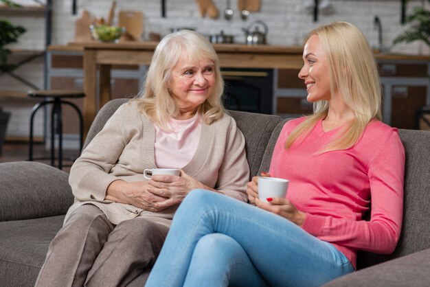 Madre e hija sentada en un sofá y tomar café