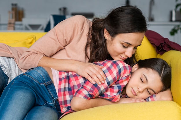 Madre e hija sentada en el sofá