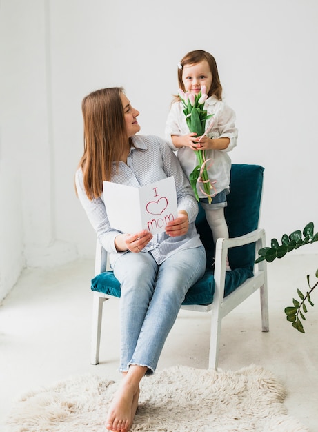 Madre e hija sentada con tarjeta de felicitación