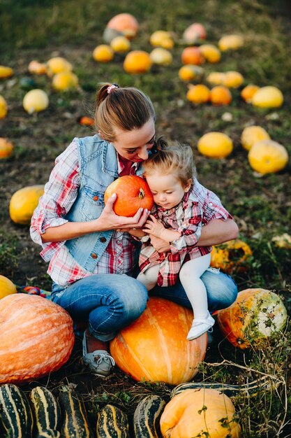 Madre e hija sentadas en calabazas, víspera de Halloween