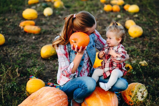 Madre e hija sentadas en calabazas, víspera de Halloween