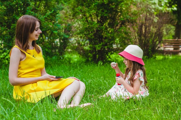 Madre e hija sentadas en el césped de un parque