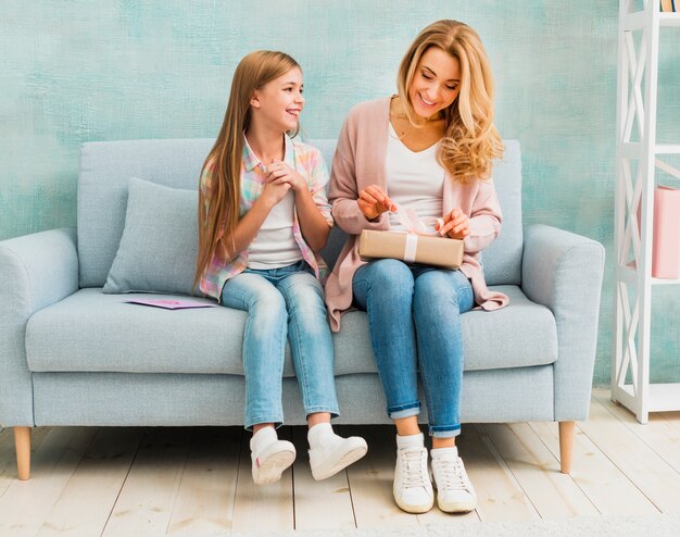 Madre e hija sentadas juntas y abriendo caja actual