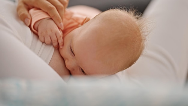 Foto gratuita madre e hija sentadas en un sofá amamantando al bebé en casa