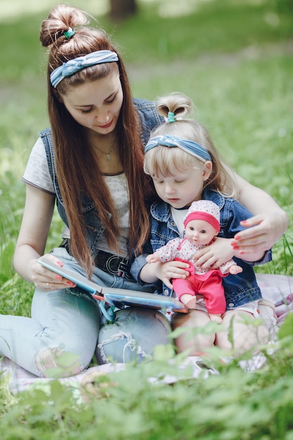 Madre e hija sentadas en el suelo leyendo un libro y la niña con una muñeca