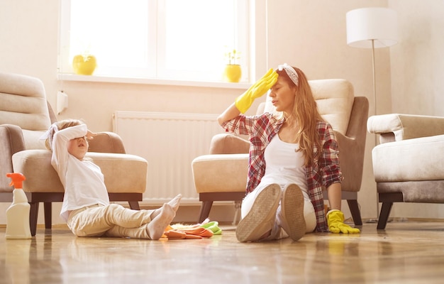 Foto gratuita madre e hija sintiéndose exhaustas después de limpiar la casa juntas