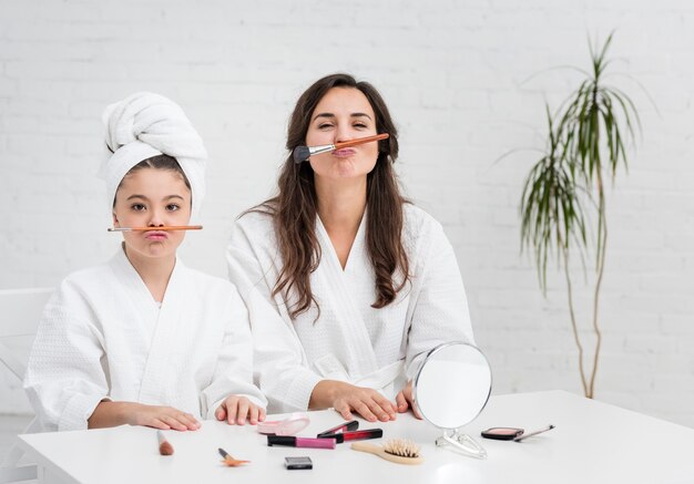 Madre e hija son tontas con pinceles de maquillaje