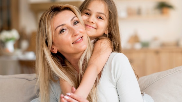 Madre e hija sonrientes abrazados en casa