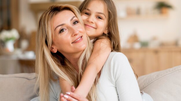 Madre e hija sonrientes abrazados en casa