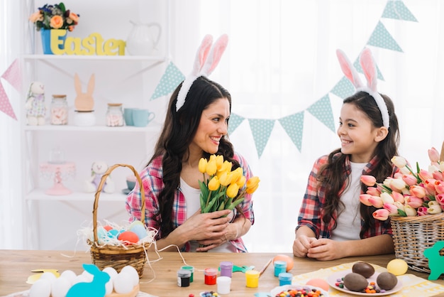 Madre e hija sonrientes celebrando el día de pascua en casa