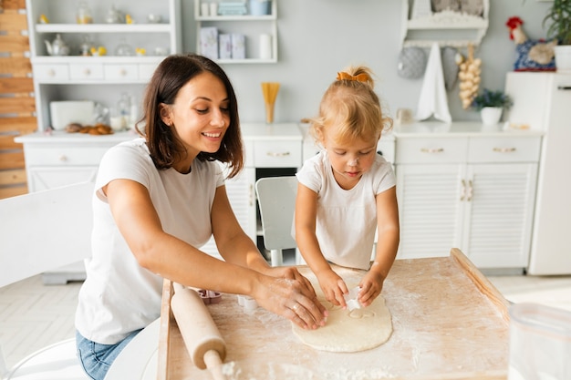 Madre e hija sonrientes preparando galletas